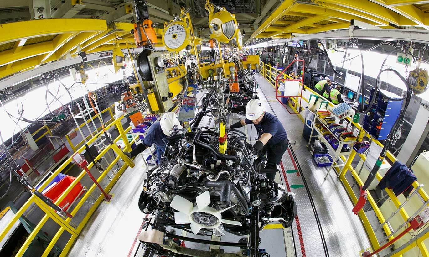 A birdseye view of two Toyota workers buidling engine pieces in the Toyota factory