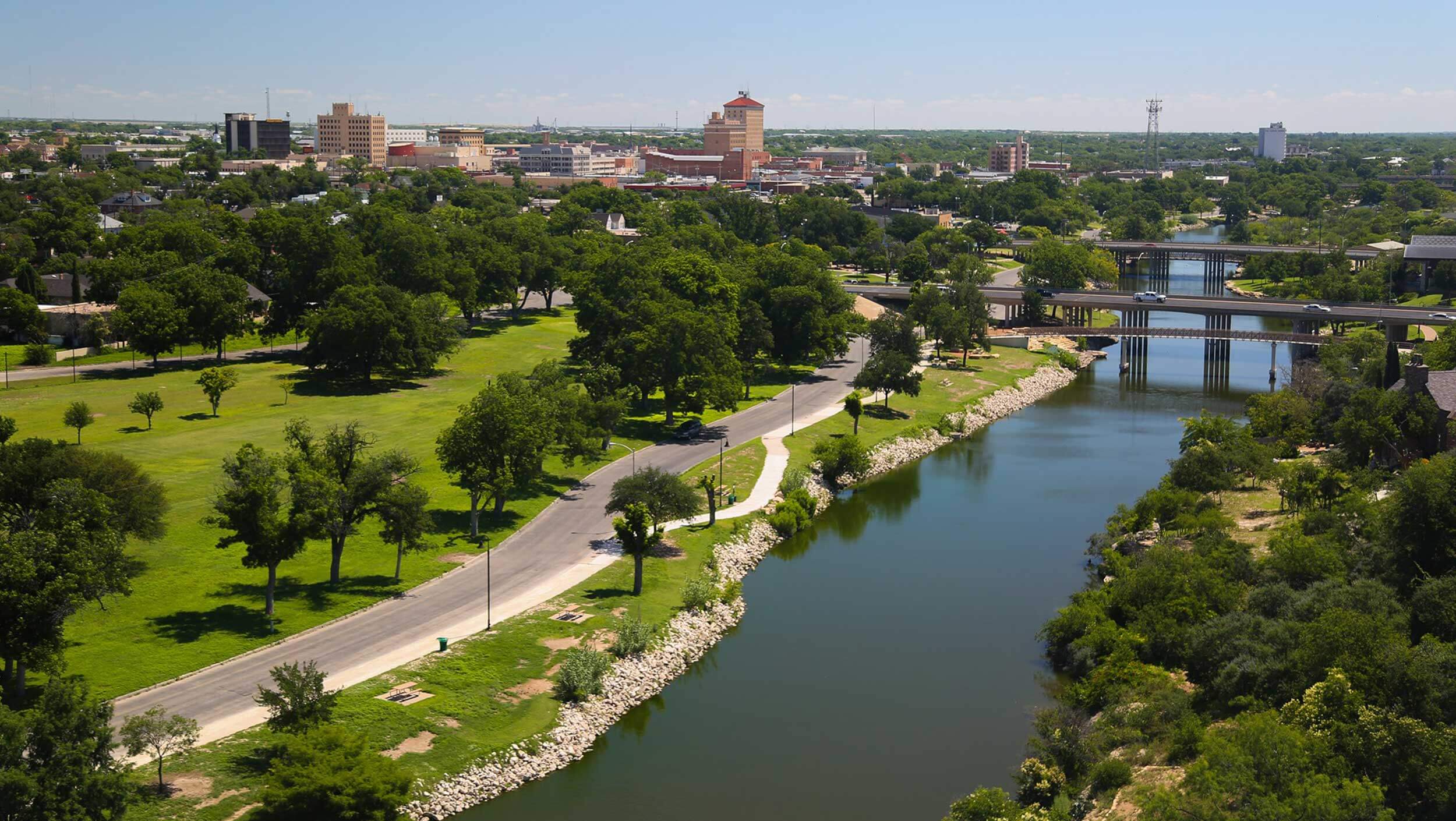 The Concho River flows near downtown San Angelo, Texas with a view of the city in the background