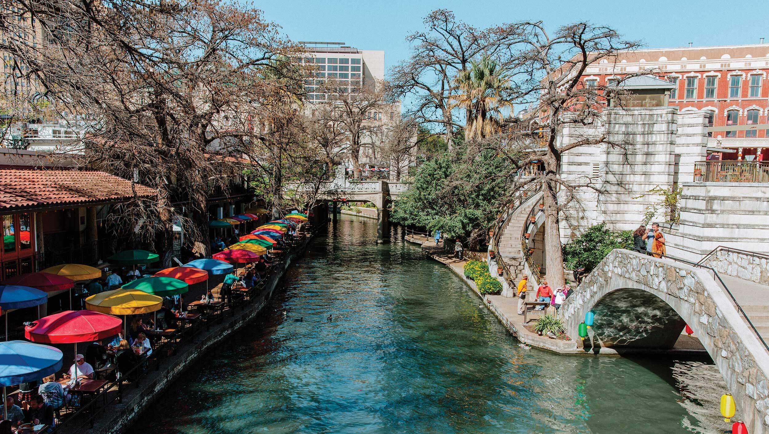 People walk alongside the San Antonio, Texas River Walk which features outdoor eateries