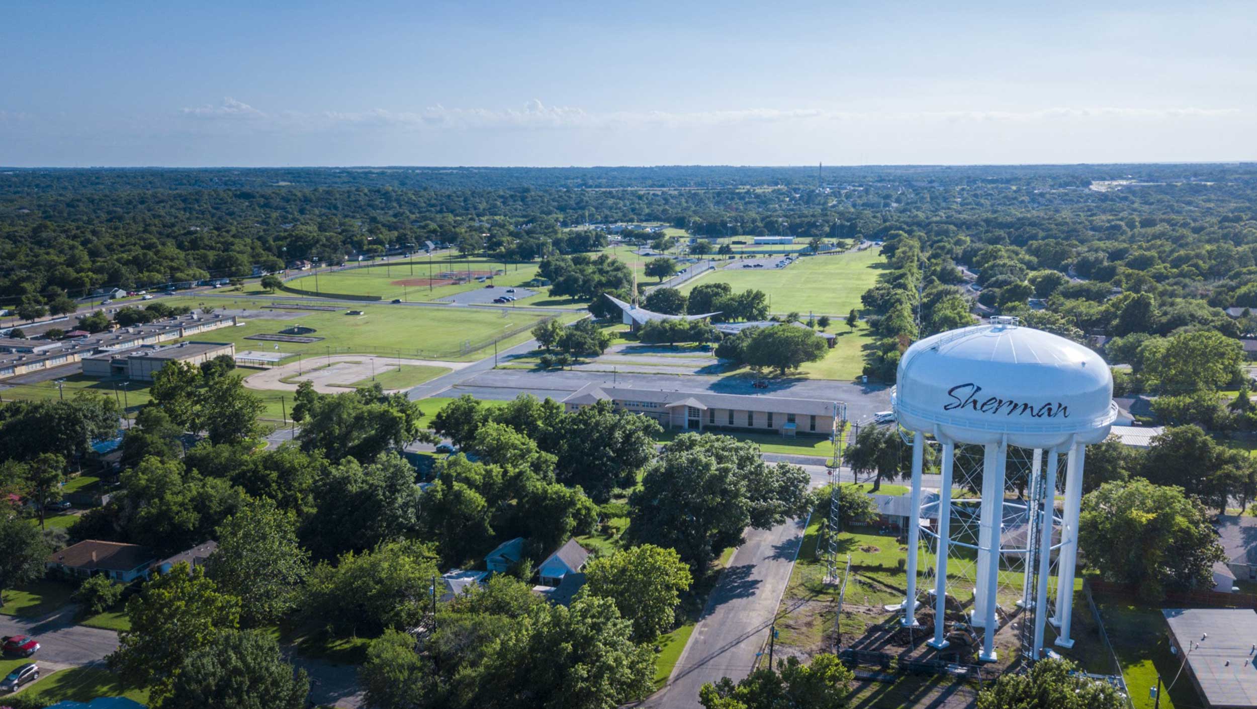 The Sherman, Texas water tower features the city's name overlooking the city's open green spaces