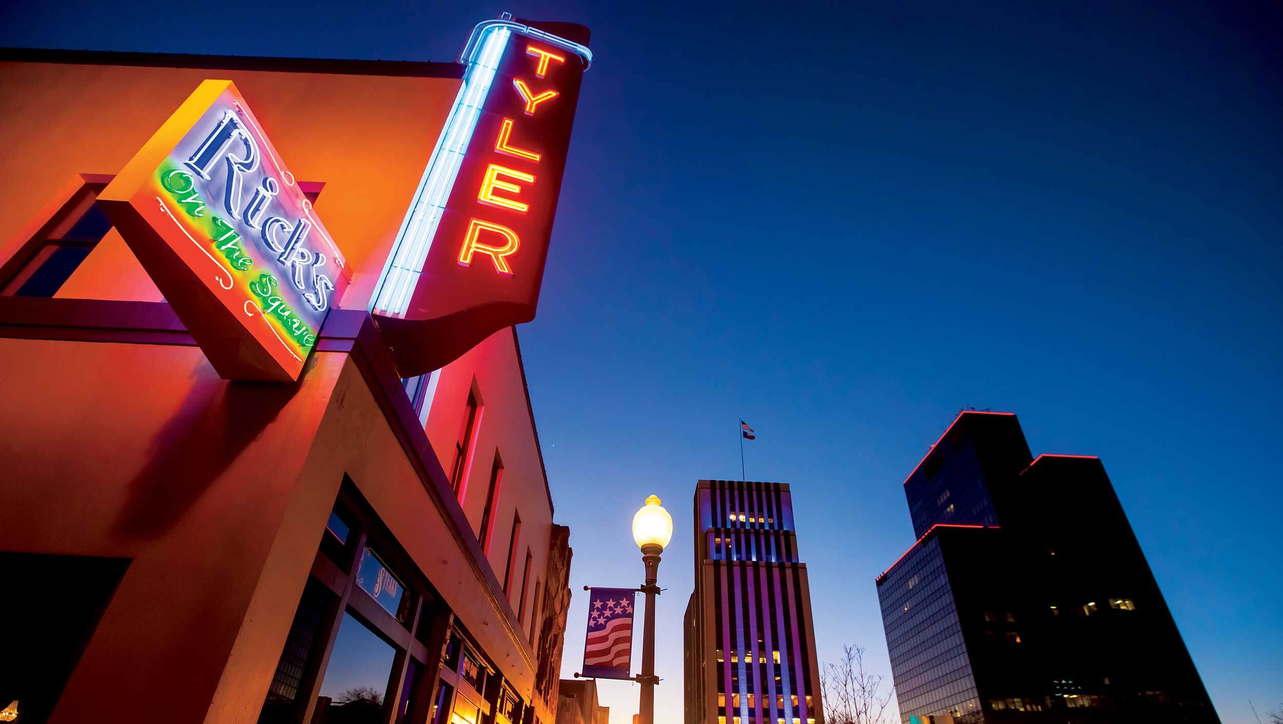 Downtown Tyler, Texas is lit up at night with neon signs