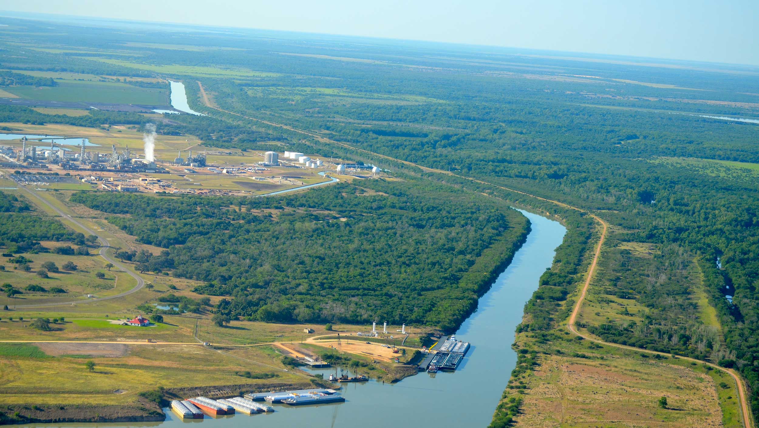 A large channel flows through the vast landscape of trees and open space at Port of Victoria, Texas.