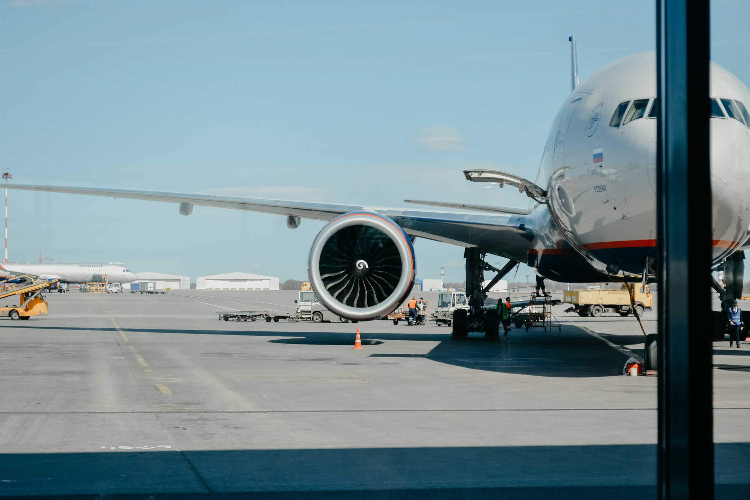 The turbine of an airplane is in focus while the plane is loaded before take off