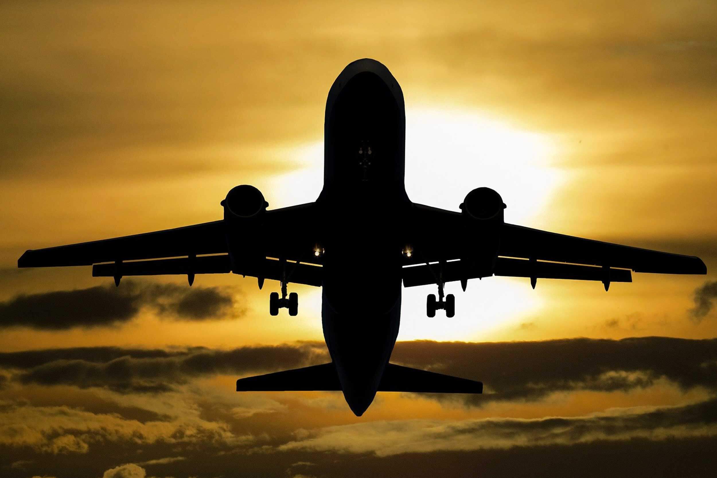 A plane soars across a sunset sky