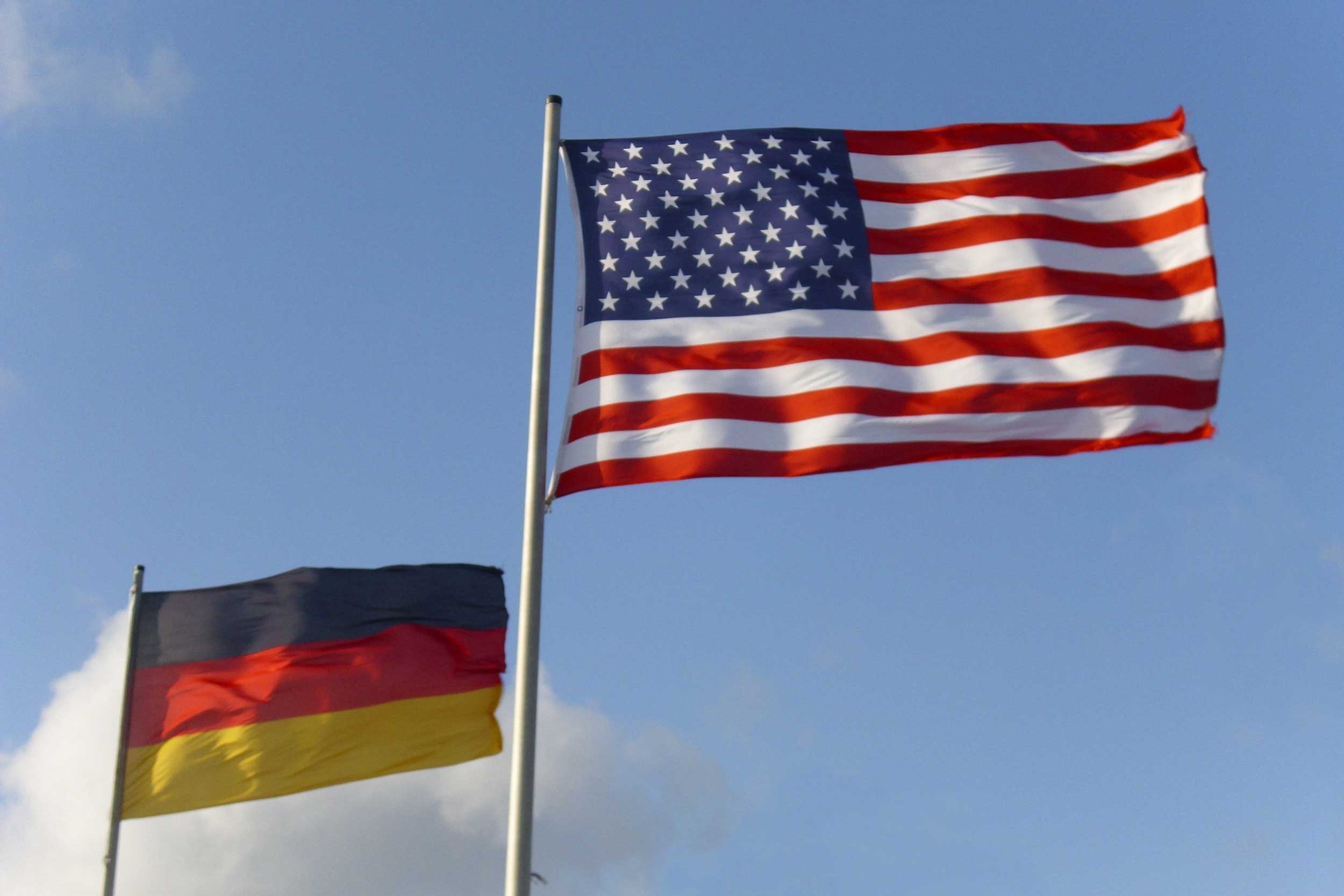 The German and US flag flying in the sky next to each other.