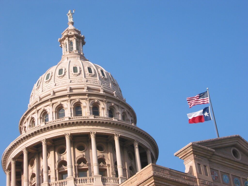 Austin, Texas Capital Building view of dome with U.S. and Texas State flag waving to the right