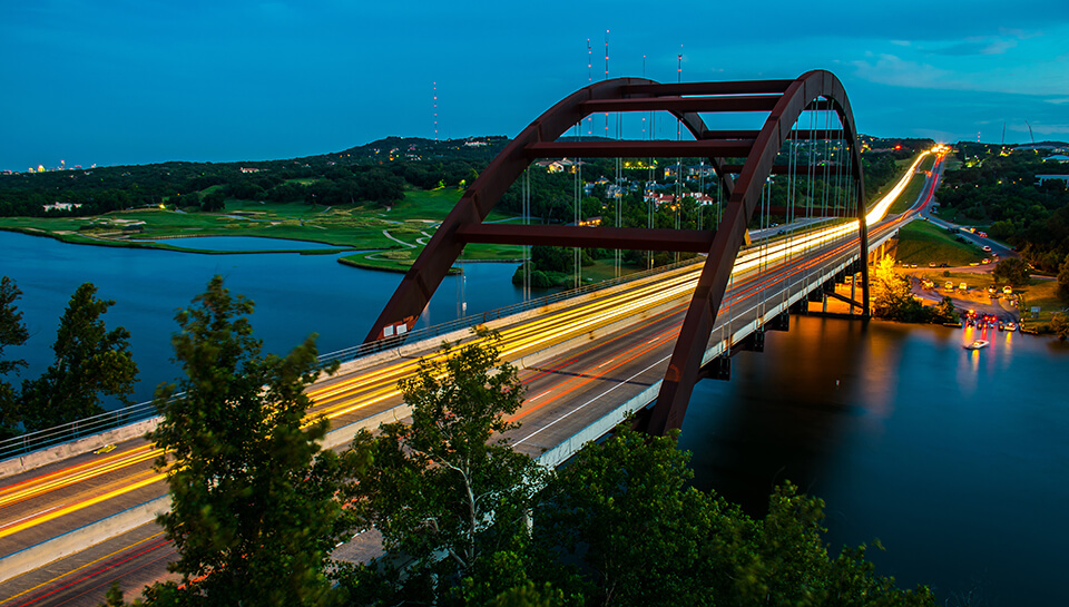 Texas 360 Bridge with passing cars driving over the Colorado River at night in Texas Hill Country