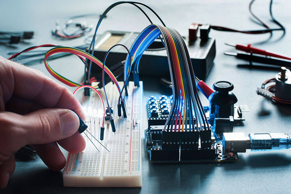 Closeup on programmer hand connecting led with breadboard and microcontroller