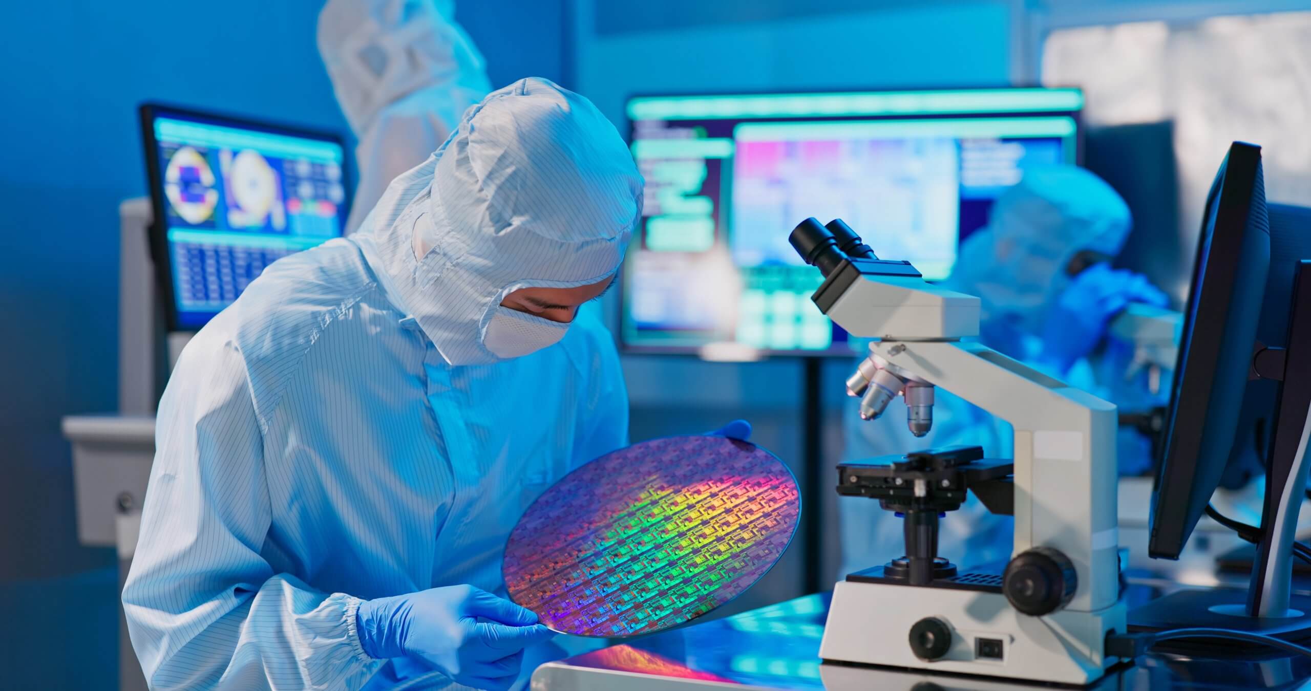 Technician In Sterile Coverall Holds Wafer That Reflects